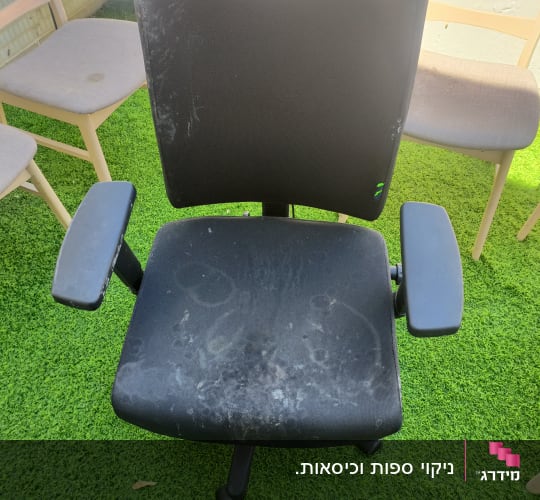 כיסא משרדי שחור עם כתמים על דשא ירוק